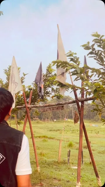 Club pennant flags on a bamboo frame at the edge of the meadow, with a rider looking out over the field.